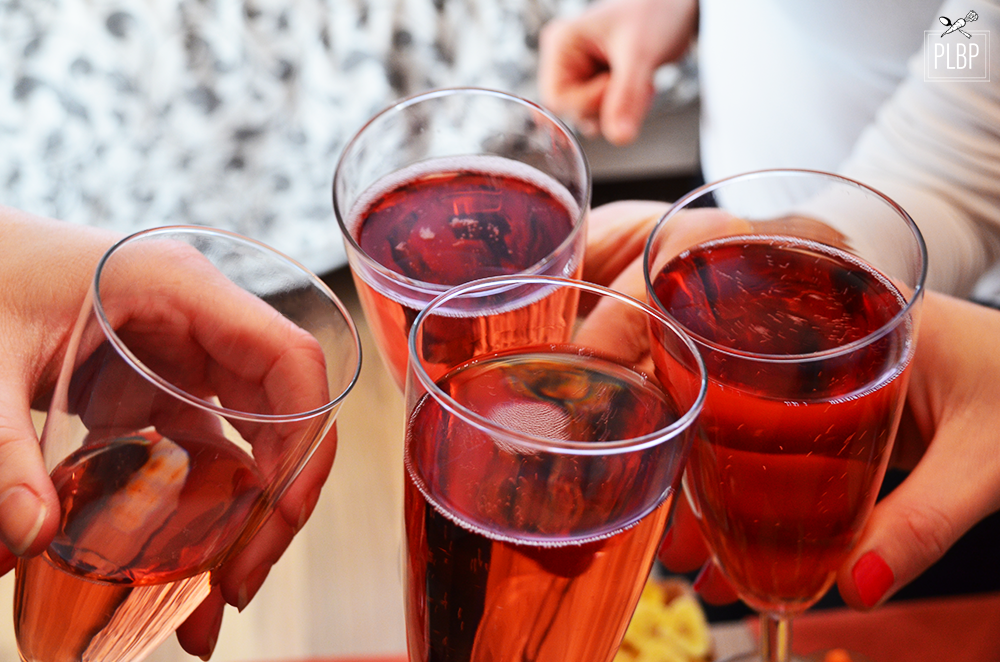 Photo de 4 mains tenant des cocktails rosés en train de trinquer.