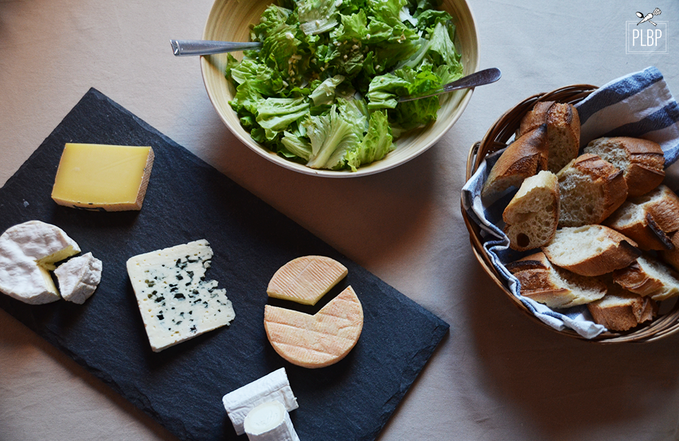 Photo d'un plateau de fromage, d'une panière, d'un bol de salade.